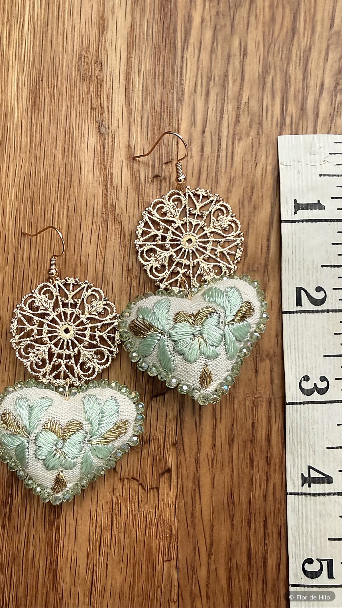 Size reference photo of the hand-embroidered heart earrings next to a ruler